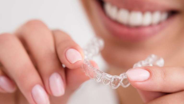 Lady holding Invisalign clear aligners at CFS Dental