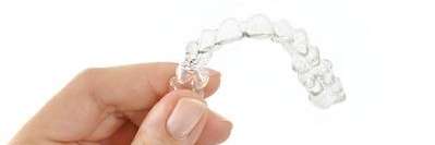 A hand holding Invisalign clear aligners at CFS Dental
